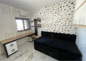 חדר שינה עם מיטה מרופדת, דולחן ומדפי עץ 