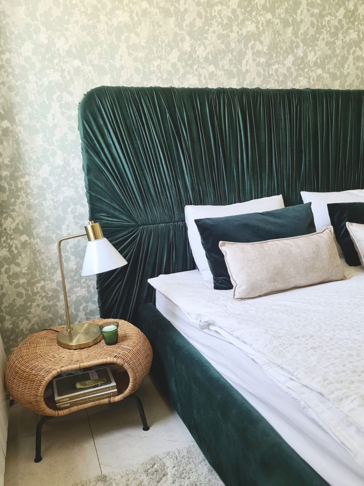 מיטה זוגית מרופדת בצבעי ירוק במבוק עם ראש מיטה גבוה ואחיד וקפלים דקורטיביים.