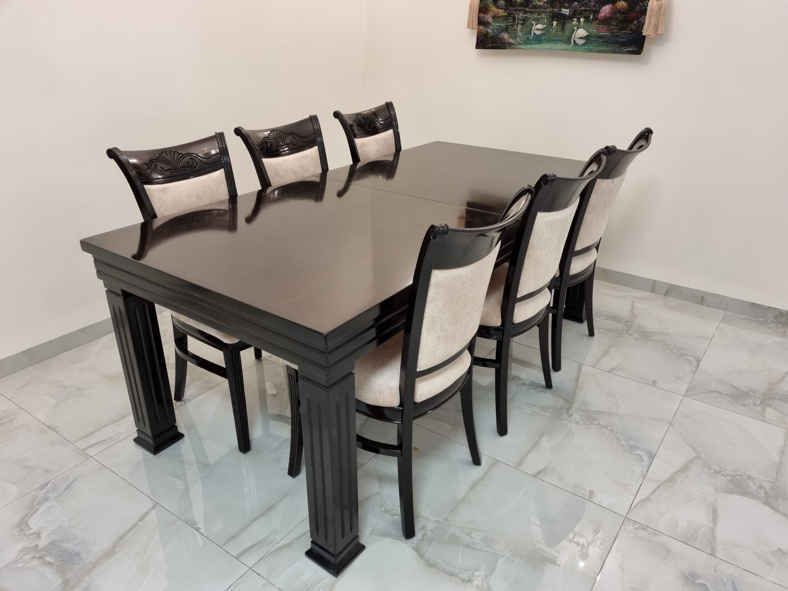 פינת אוכל אלגנטית הכוללת שולחן עץ כהה בעיצוב קלאסי עם רגליים מעוצבות ושישה כיסאות מרופדים עם מושב וגב מרופדים בהתאמה .