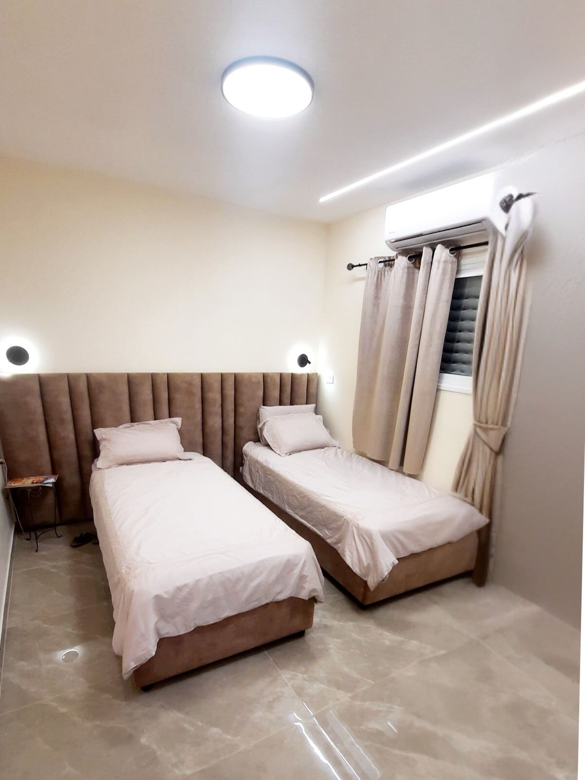 מיטה זוגית עם ראש מיטה רחב בעיצוב תיפורים אנכיים ובסיסים מרופדים תואמים.