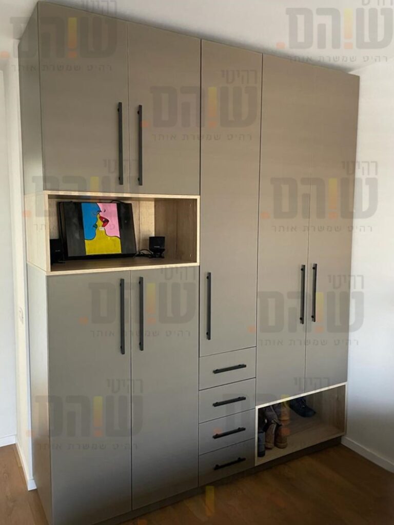 ארון בגדים עם חזית אחידה בגוון ניטרלי, ידיות שחורות, נישה פתוחה בגימור עץ, מגירות ואזורי אחסון משולבים.