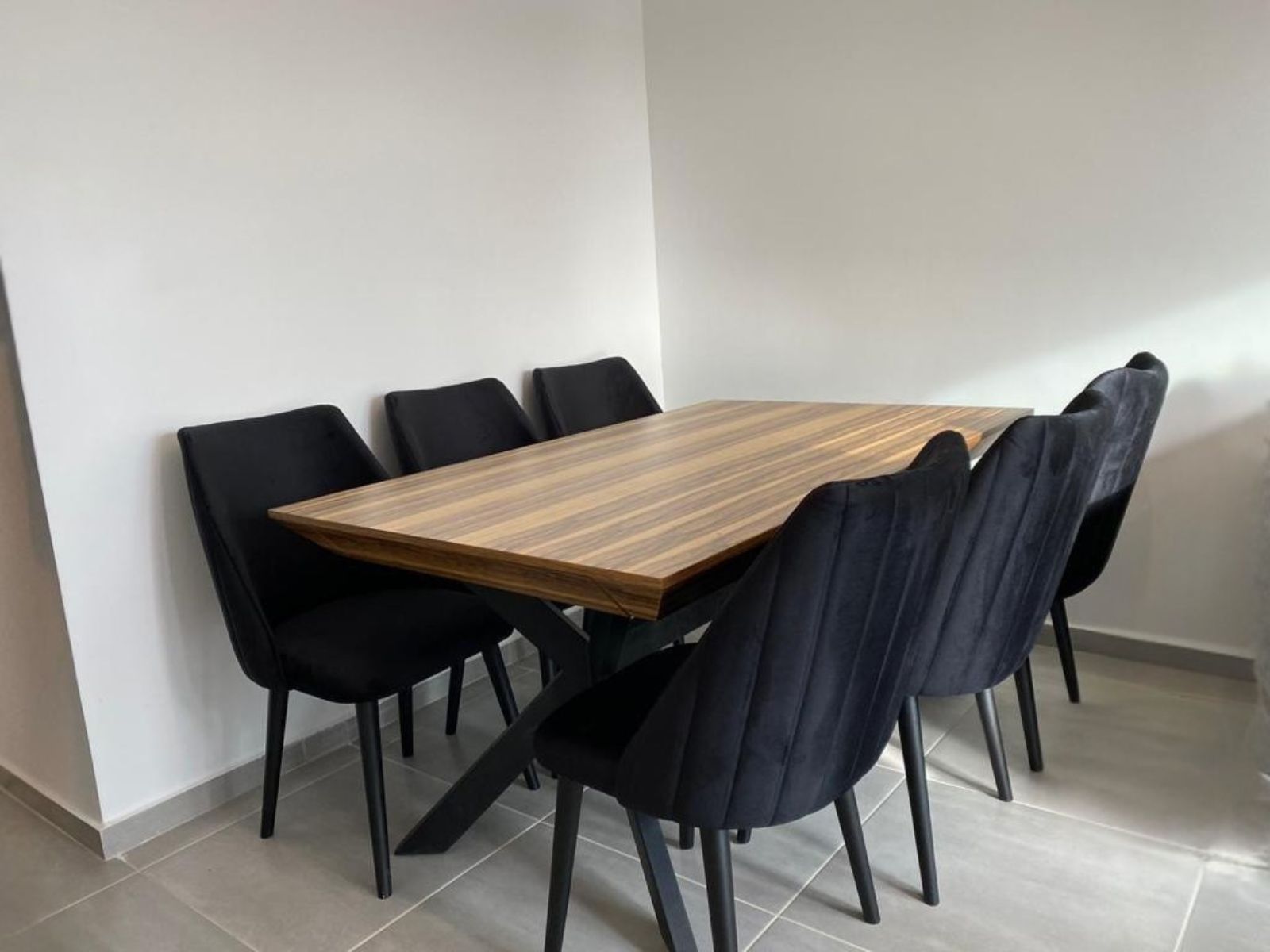 שולחן אוכל מעץ עדכני עם כסאות שחורים מרופדים בדיגום אנכי