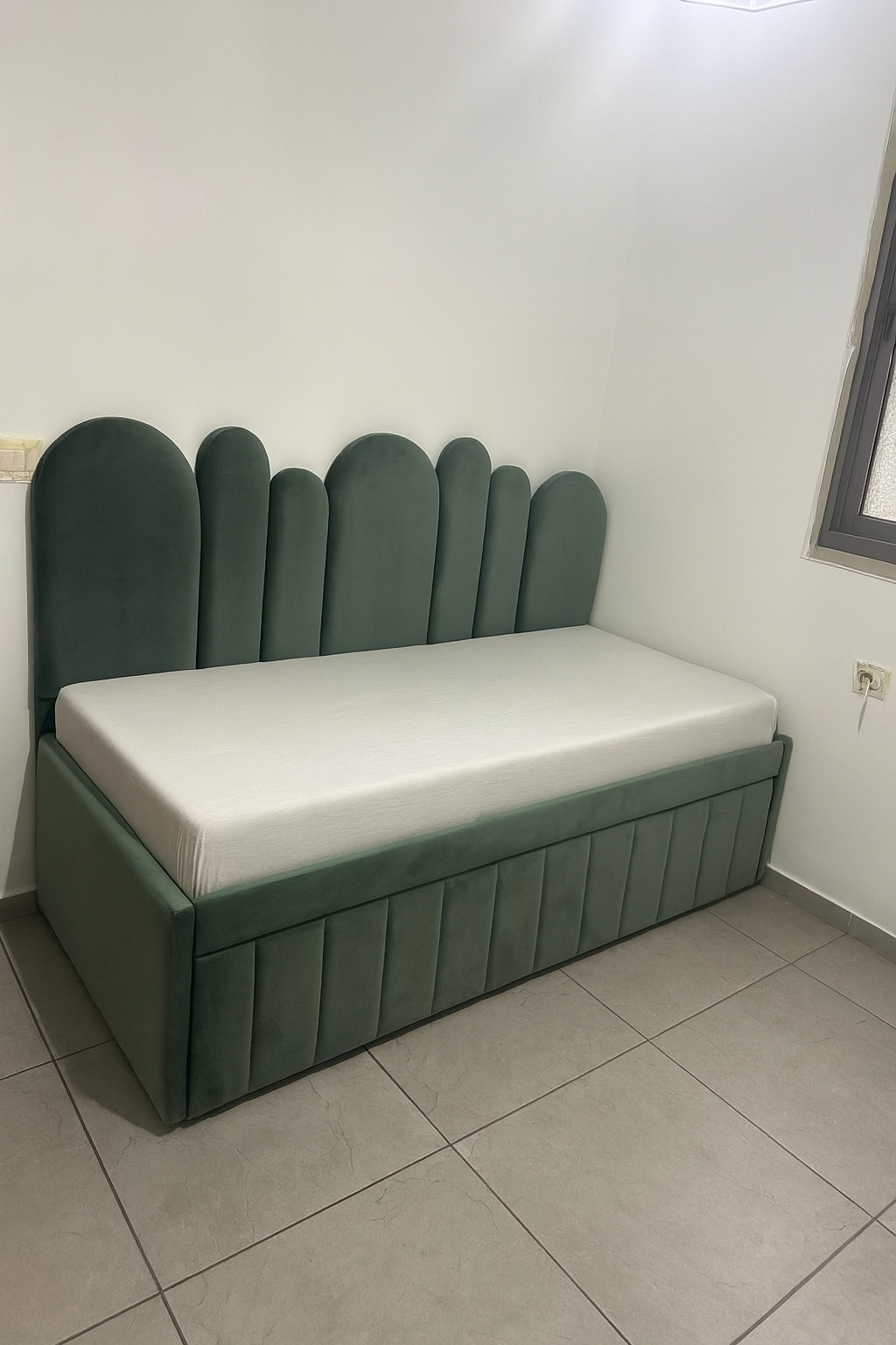 מיטת נוער מרופדת בגוון ירקרק, עם ראש מיטה בעיצוב קמור ובסיס מרופד בקווים נקיים.