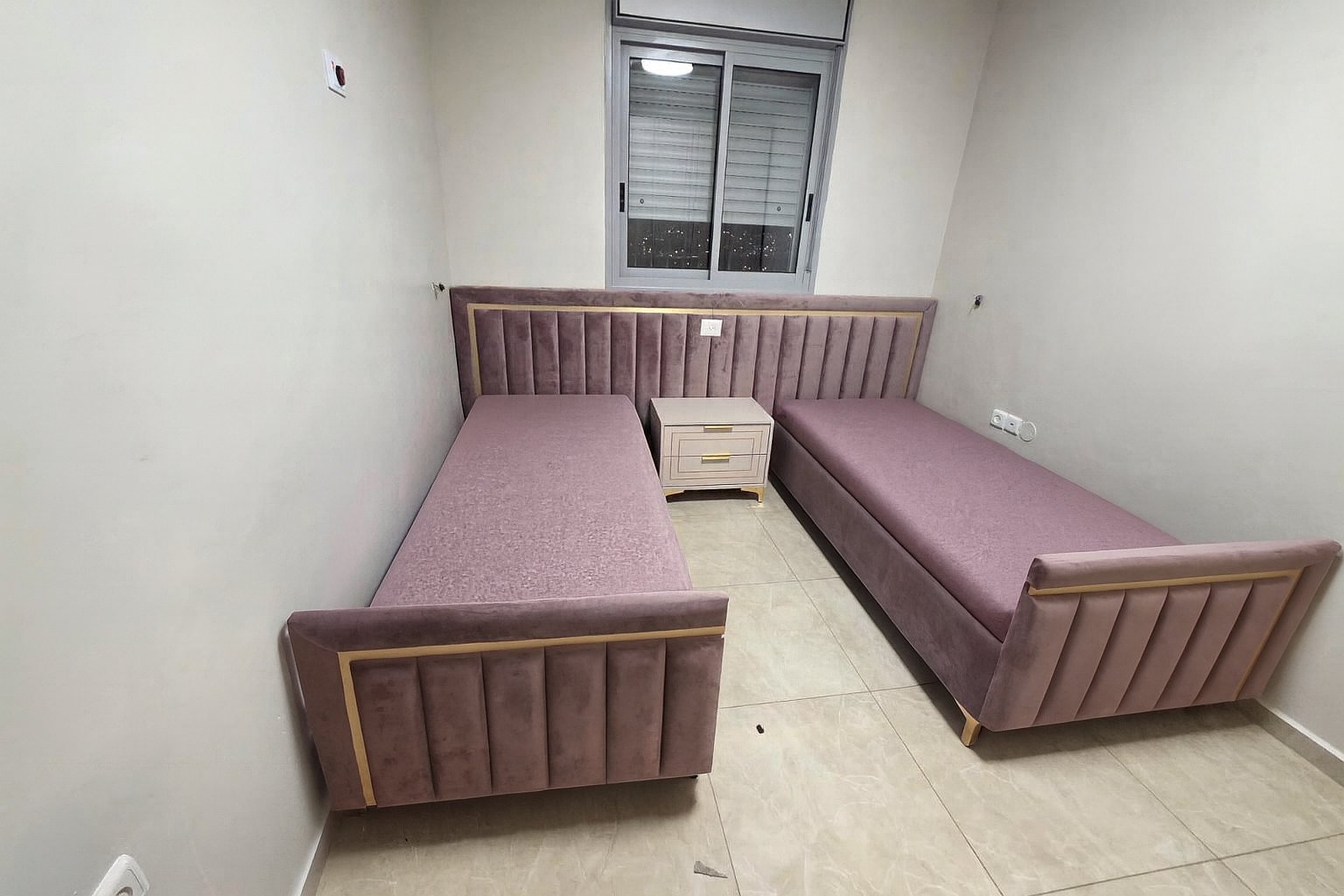 מיטות חדר שינה מעוצב עם מיטות יחיד מרופדות, ראש מיטה רציף בגוון סגלגל ונגיעות זהב