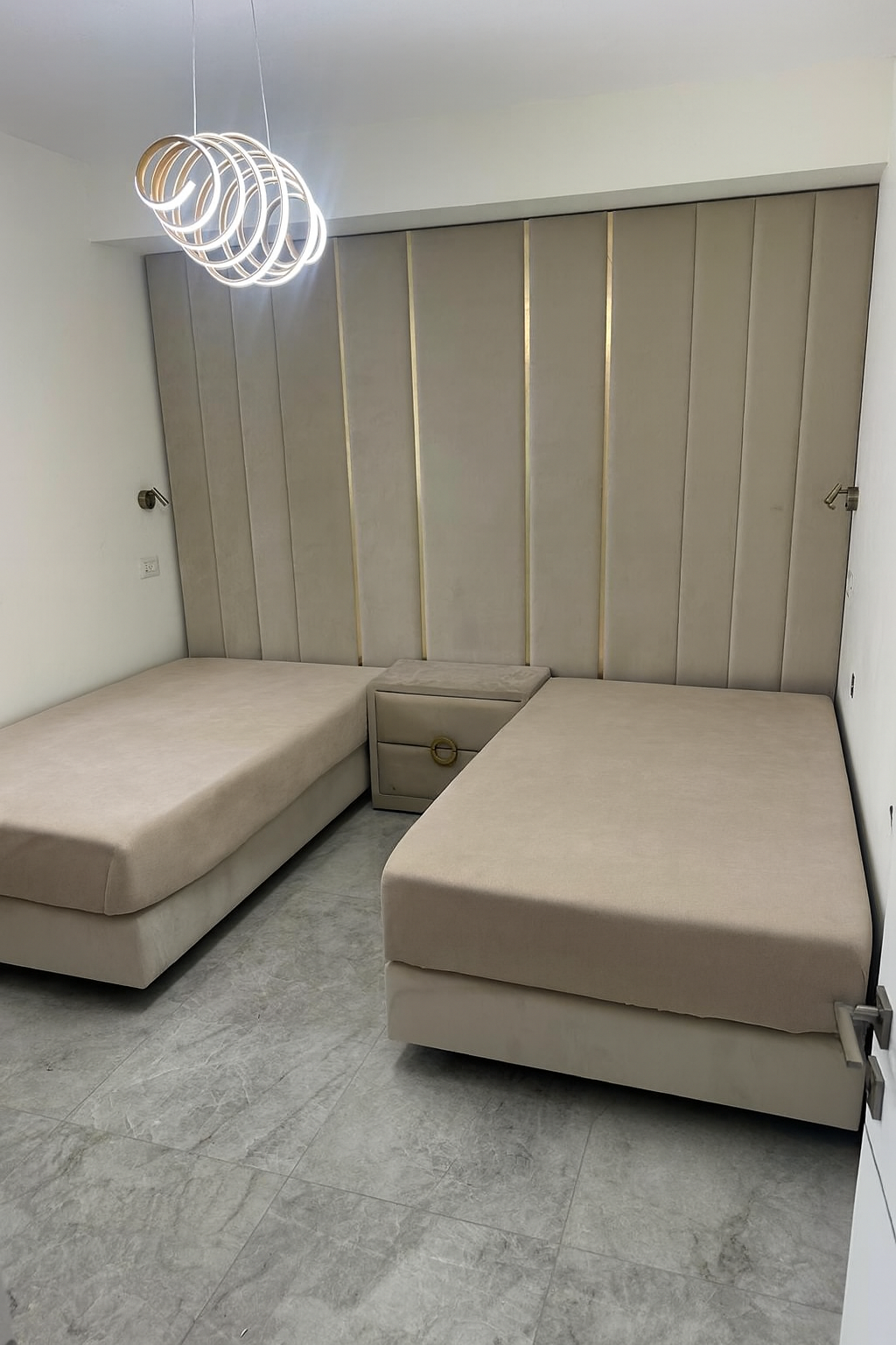 מיטות חדר שינה עם ראש מיטה יוקרתי המשתלב לאורך הקיר בעיצוב נקי עם נגיעות זהב עדינים