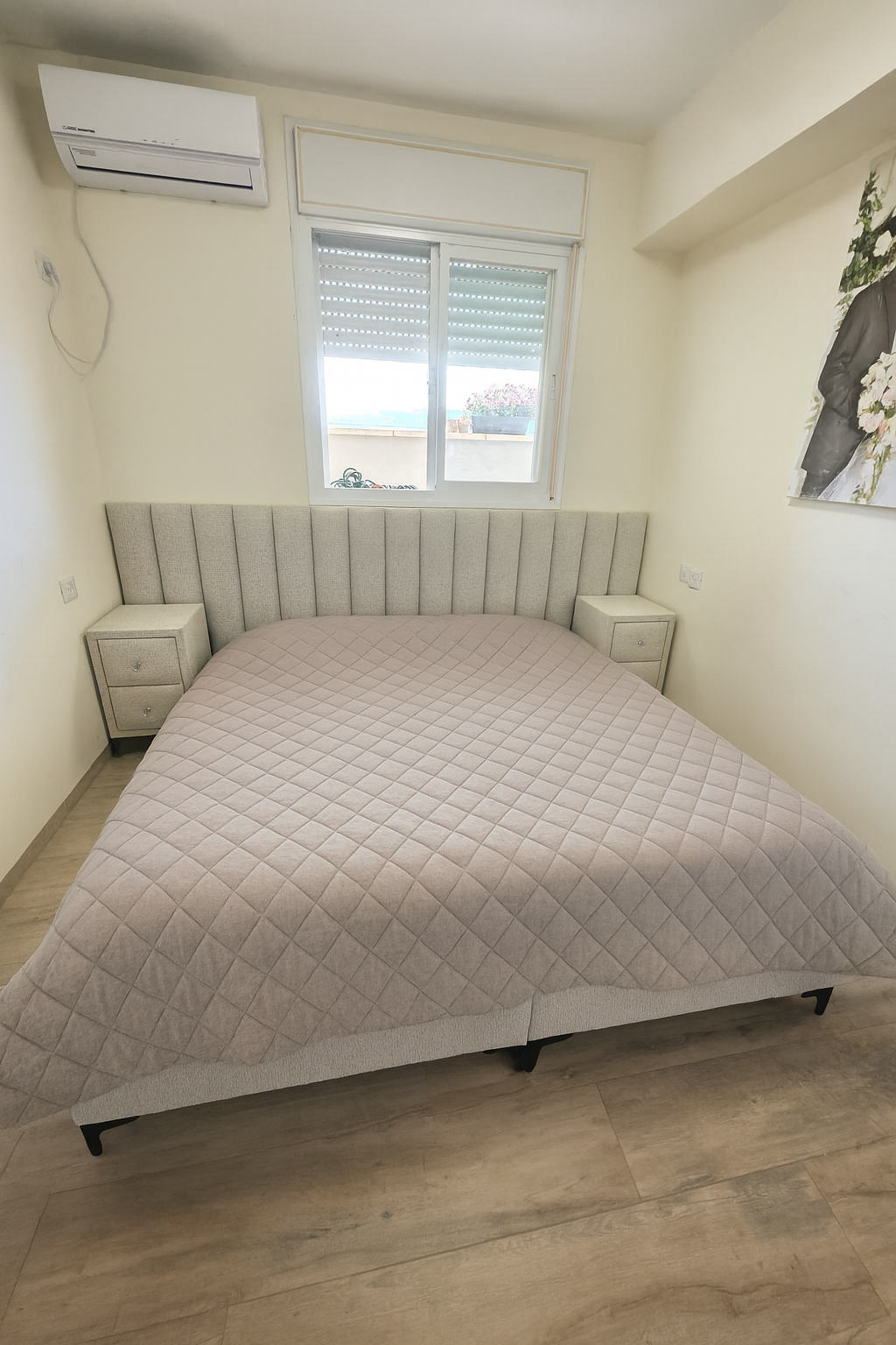 מיטה זוגית מרופדת עם ראש מיטה בדיגום אנכי ושידות לילה תואמות בגוון בהיר