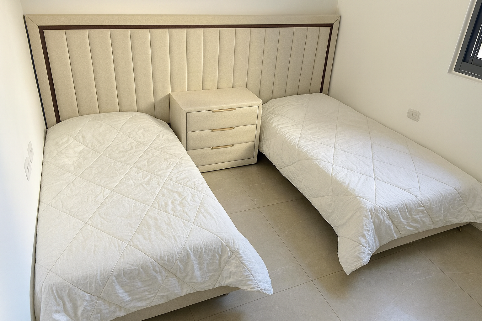 מיטות חדר שינה מרופדות בצבע שמנת מעודן , וראש מיטה רציף בדיגום אנכי עם מסגרת עץ עדינה