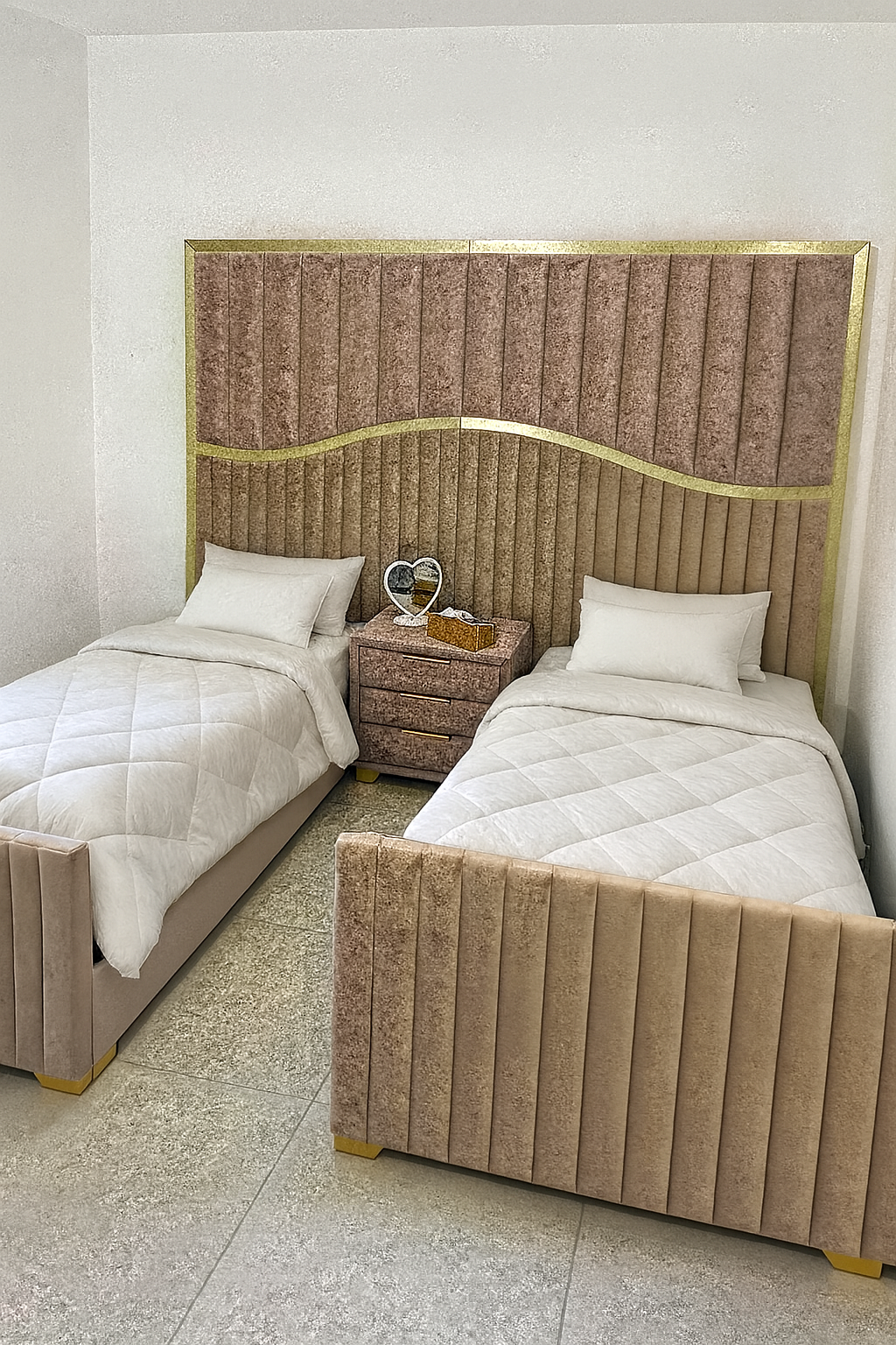 מיטת חדר שינה מרופדת בצבע ורוד נסיכותי עם ראש מיטה רציף בדיגום אנכי עם קו גלי ושילוב מסגרת זהב