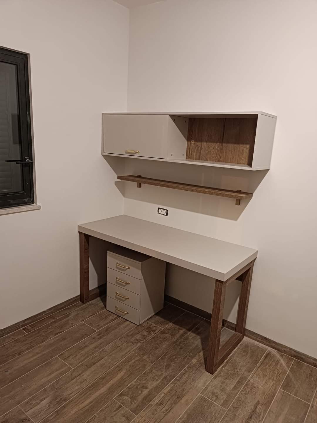 שולחן עבודה בעיצוב נקי עם משטח בהיר ורגלי עץ, וכוורת עם שילוב תא סגור ונישה פתוחה בגימור עץ.