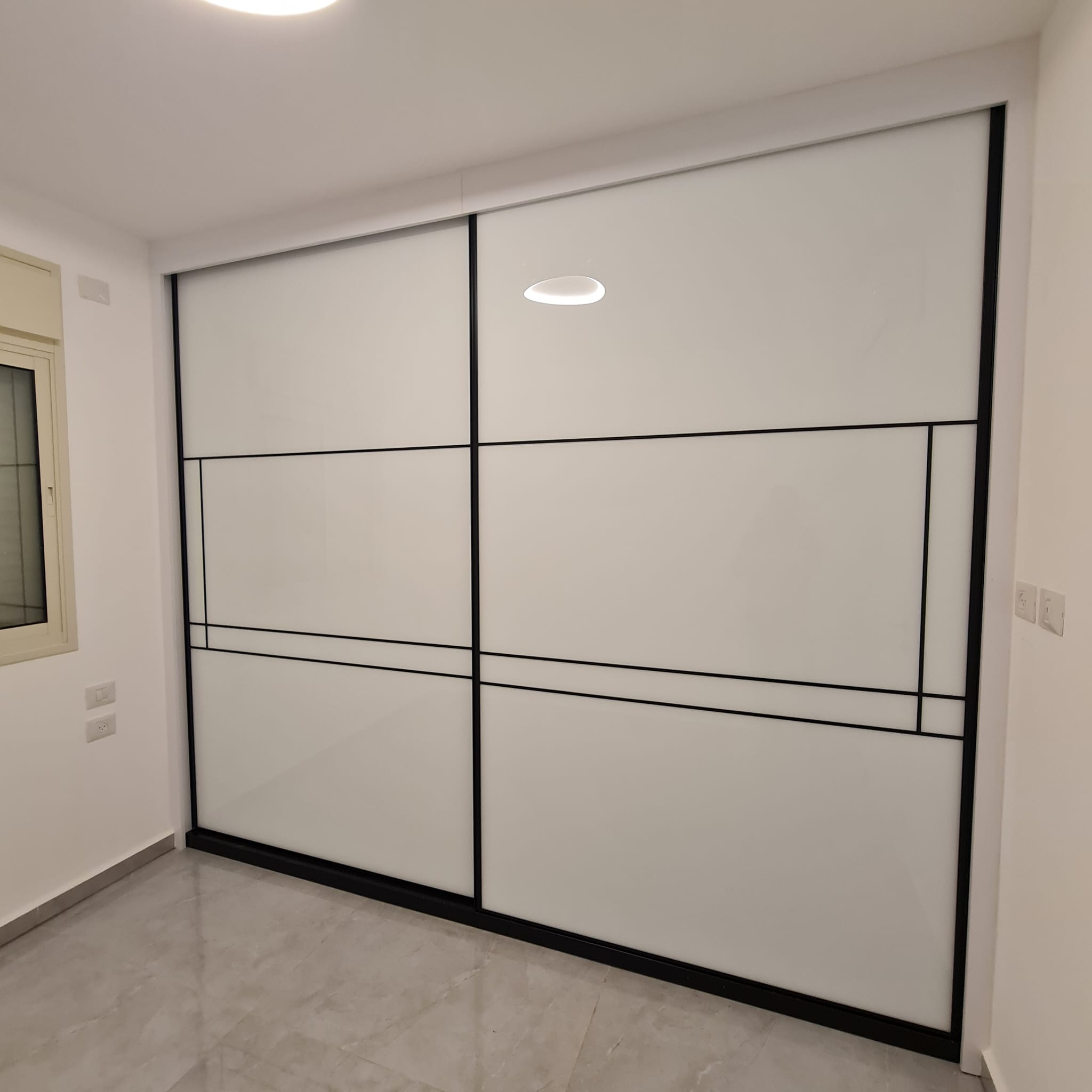 ארון הזזה פרמיום עם דלתות לבן חלבי משולב פרופיל שחור דק בעיצוב גאומטרי מודרני ונקי