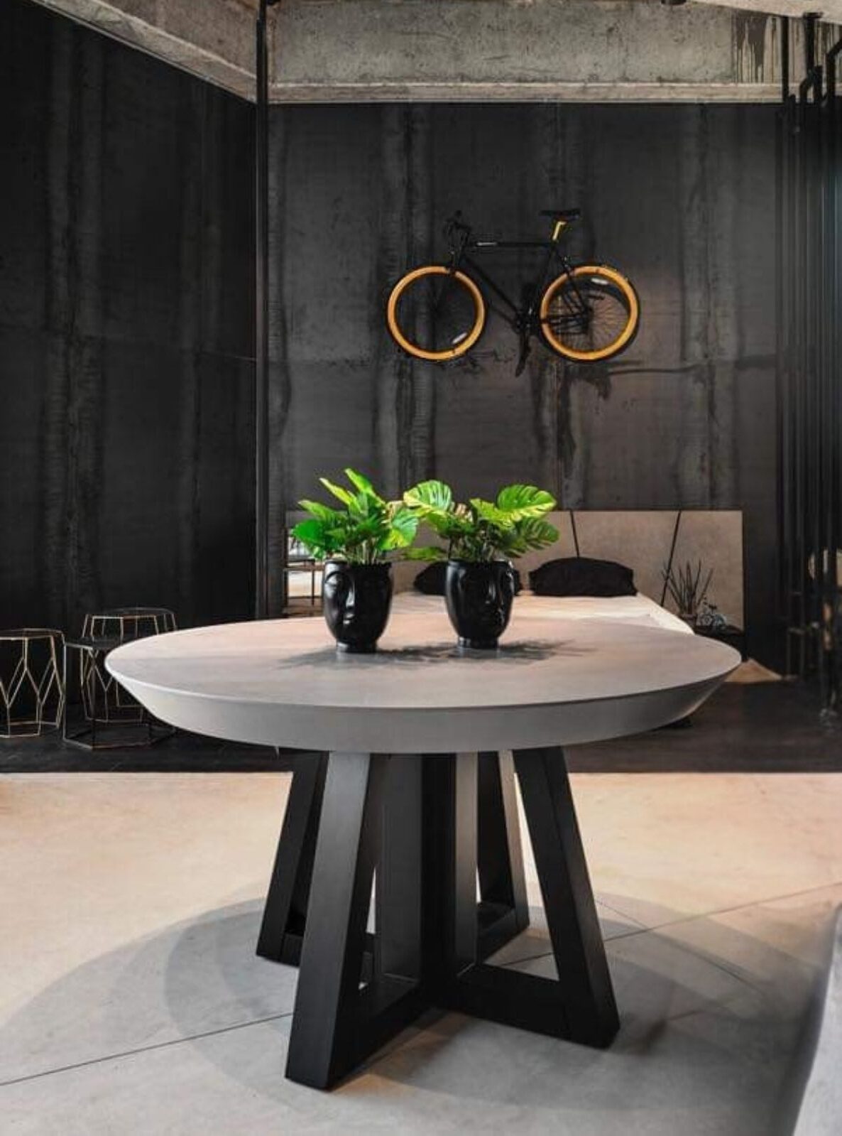 שולחן אוכל עגול (נפתח )עם משטח בהיר ורגל מרכזית שחורה פיסולית.