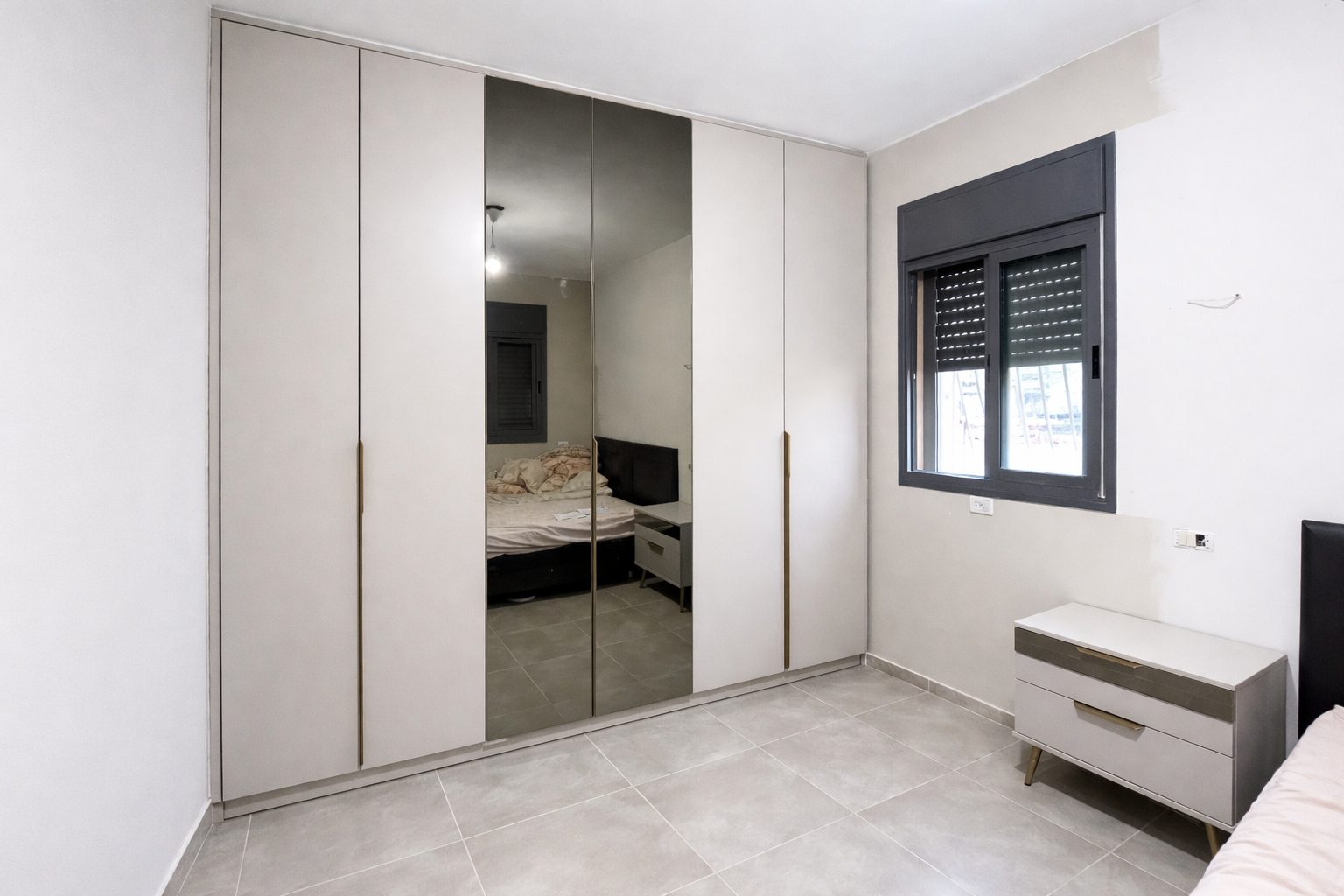 ארון פתיחה בצבע בהיר עם שילוב ידיות ארוכות ודלתות מראה עם שידה מעוצבת בהתאמה